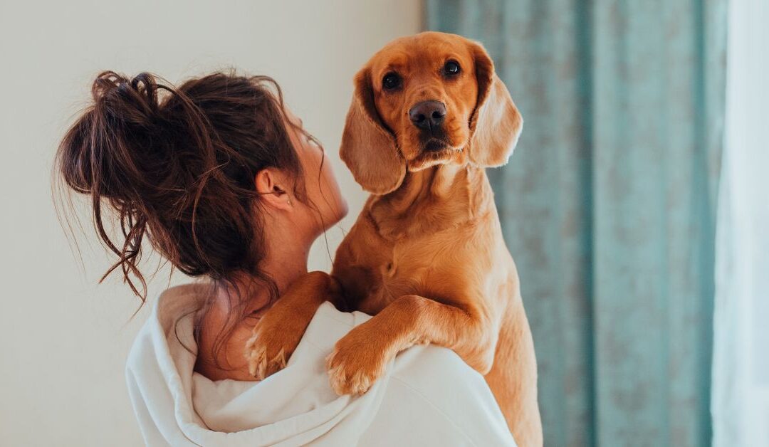 Woman holding dog over her shouler